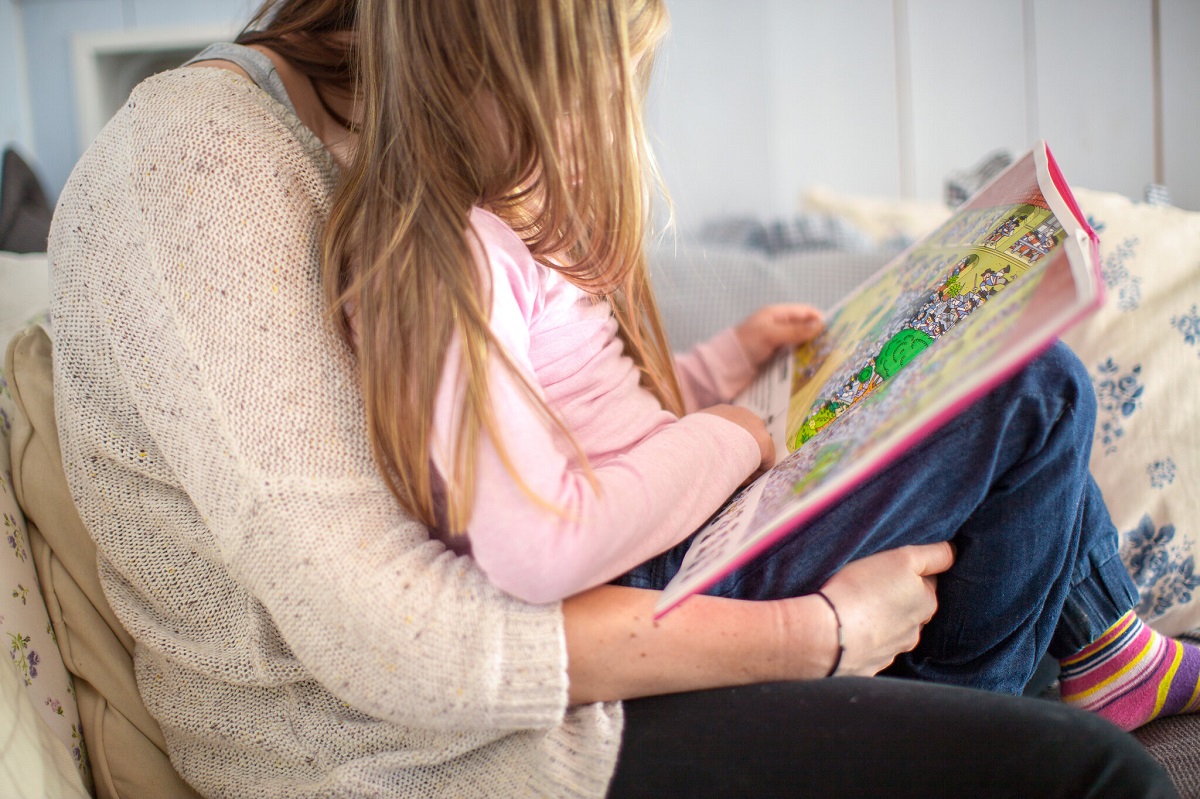 jente sitter på fanget til sin mor og leser