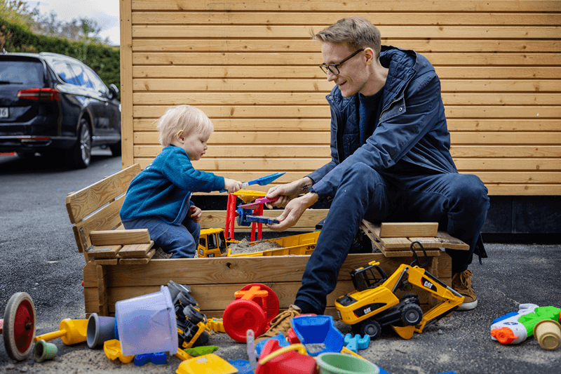 Far og sønn leker i en sandkasse