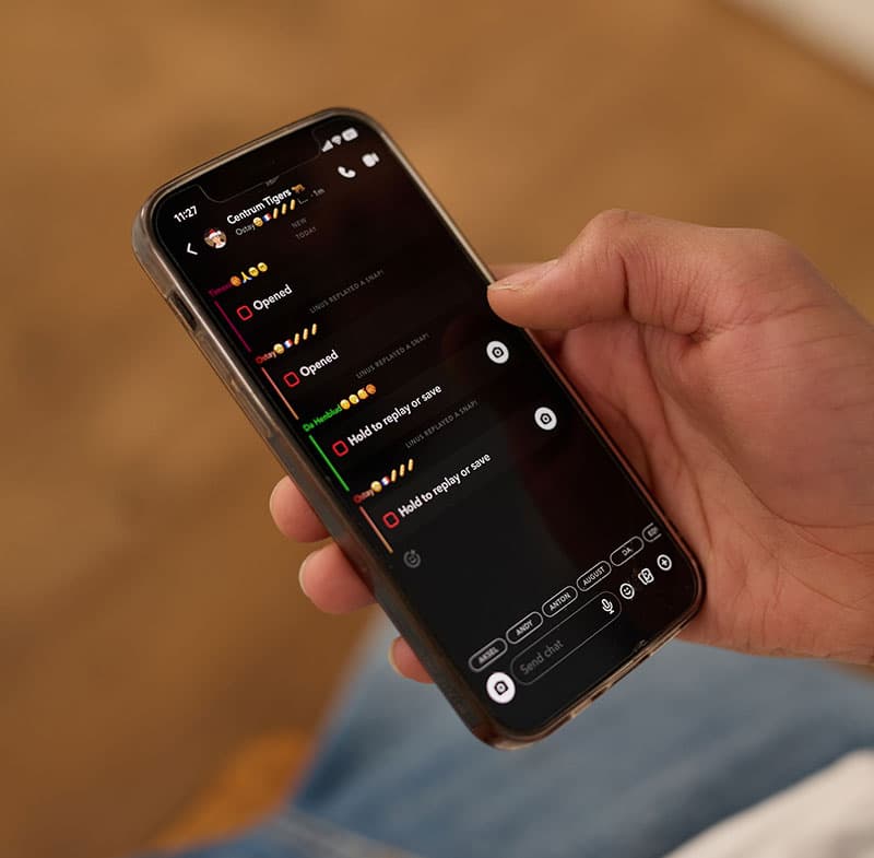 Hånd holder en mobiltelefon som viser meldinger i en chattetjeneste.