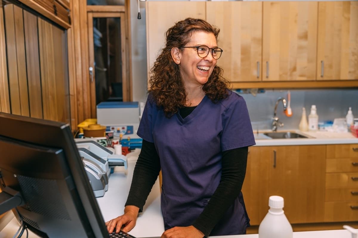 Fastlege Ellen Fagerberg står på kontoret og smiler