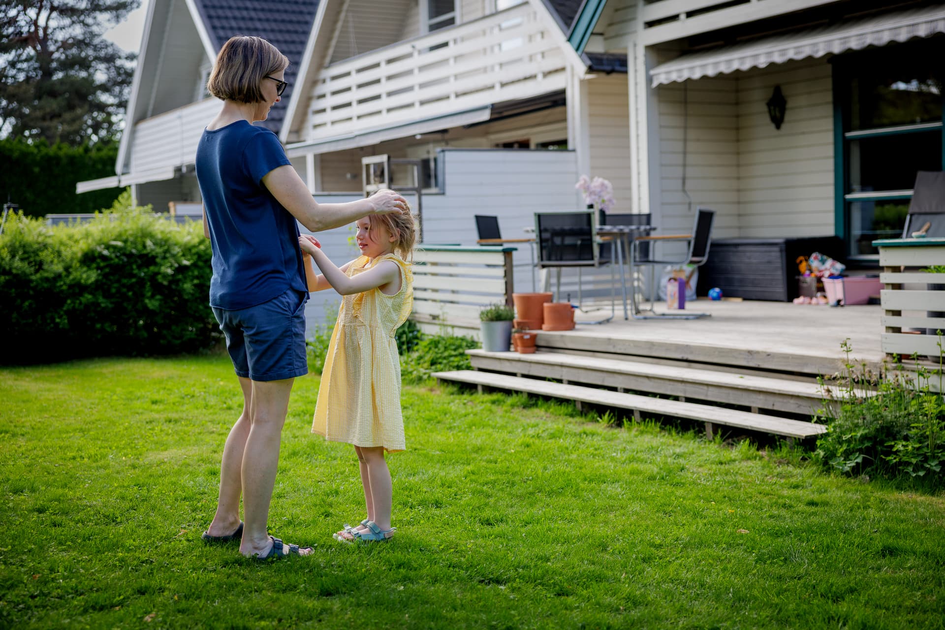 Voksen og barn står sammen i en hage utenfor et hus