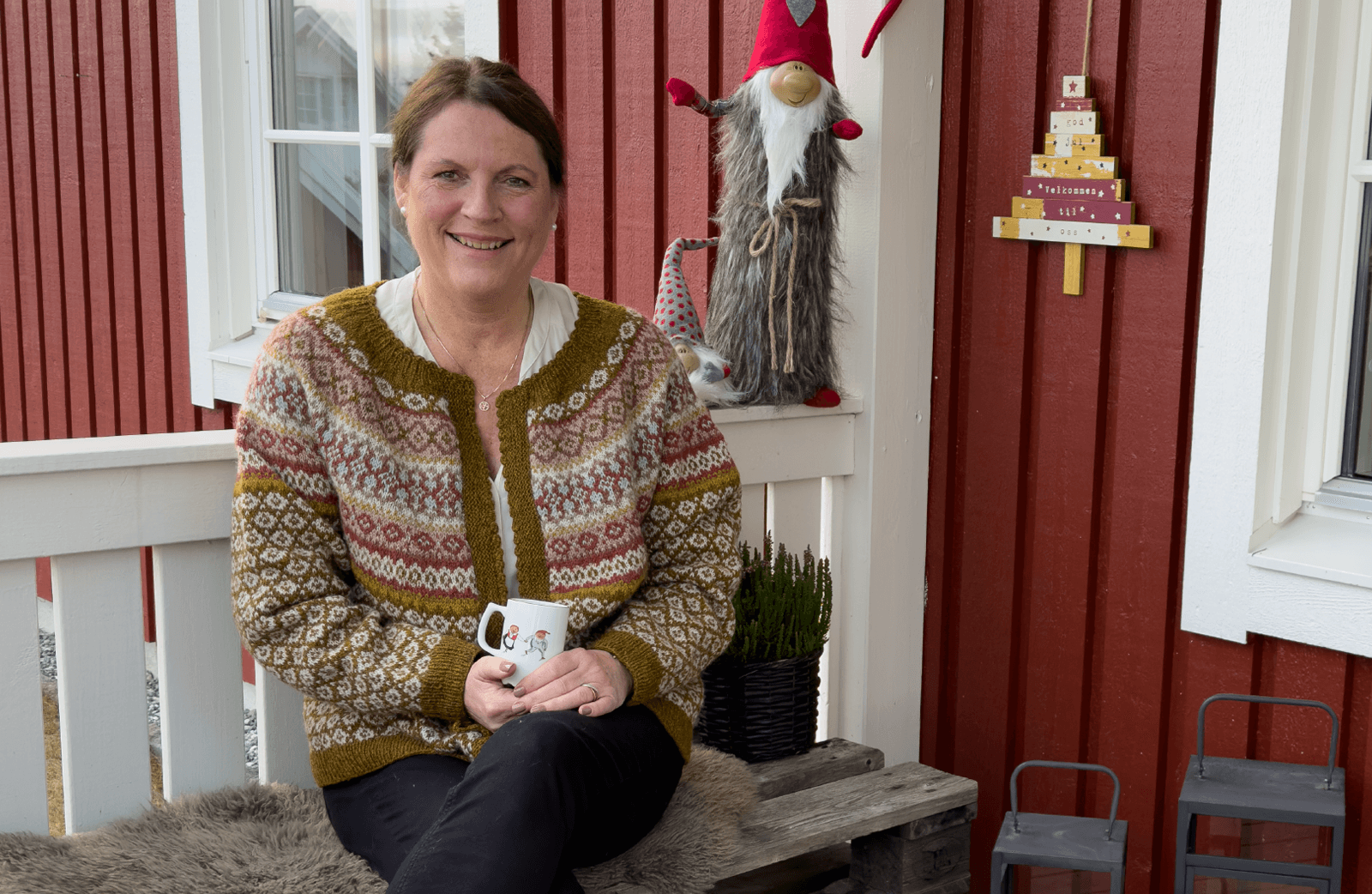 En mørkhåret dame med julenisser på verandaen