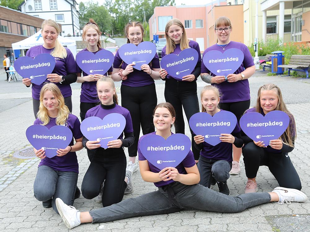 10 jenter med lilla hjerteplakater poserer for kamera