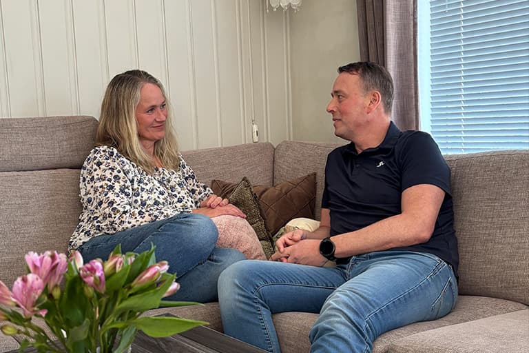 Kvinne og mann sitter i en sofa mannen
