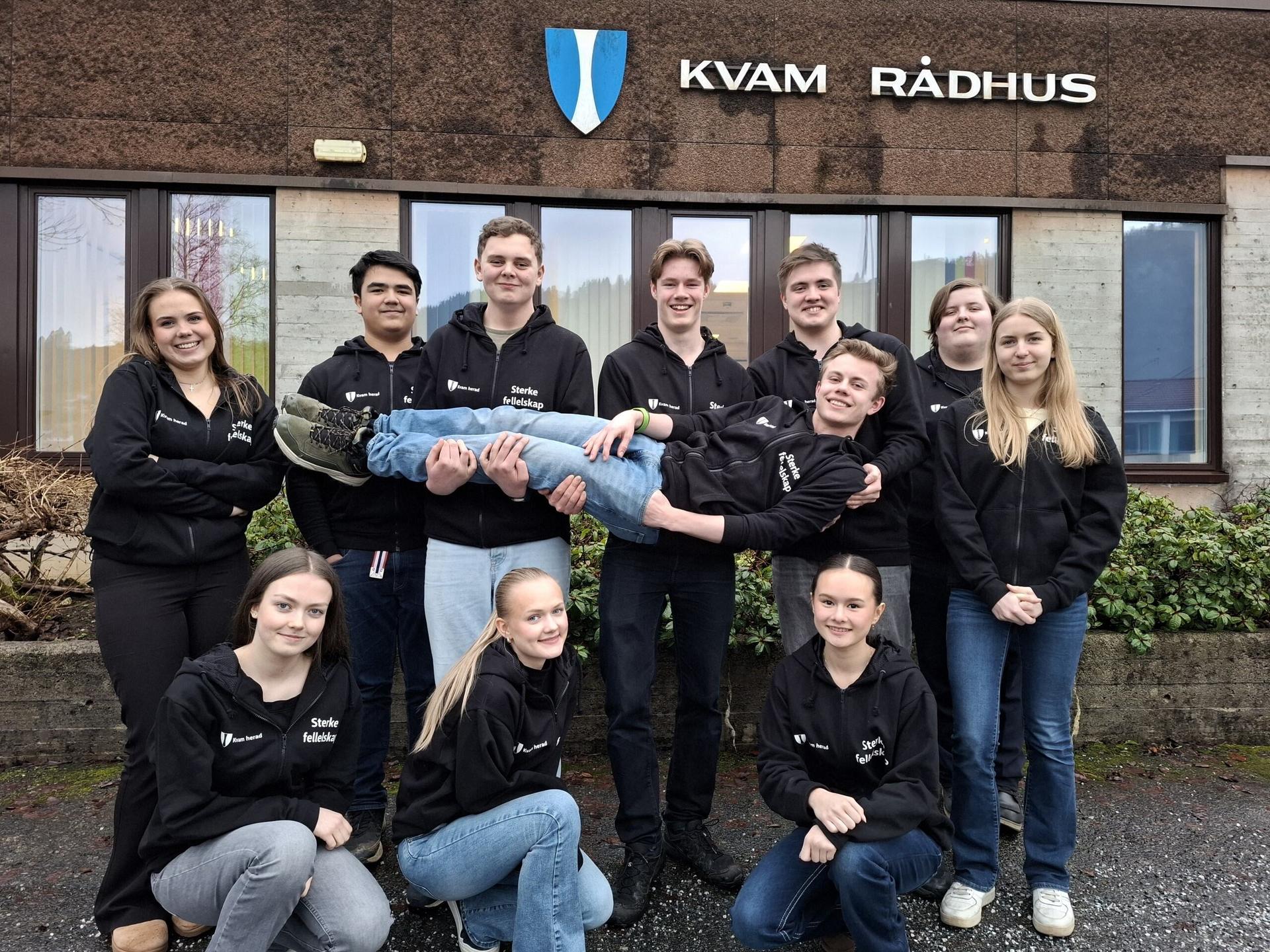 Ungdommene i Kvam ungdomsråd utenfor Kvam rådhus i sorte hettejakker. 