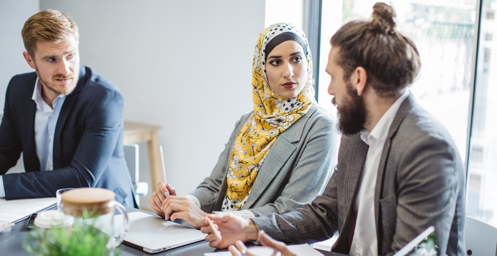 To menn og en kvinne som snakker sammen ved et bord.