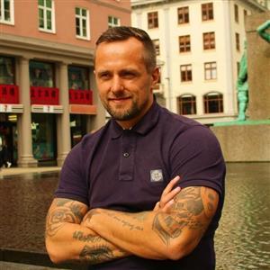 portrett av mann foran bygninger og statue