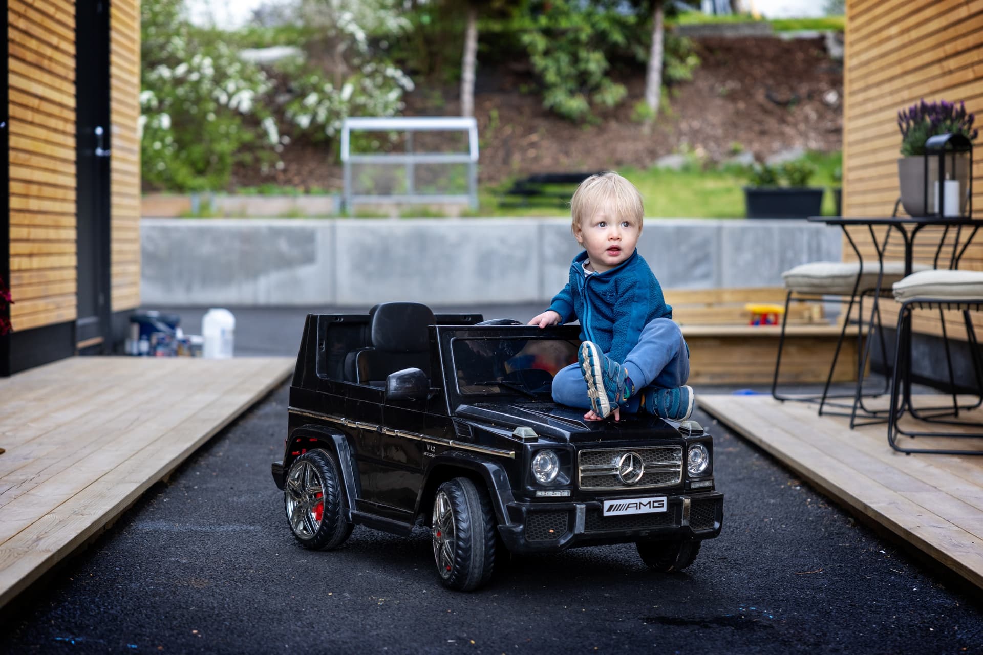 Lite barn sitter på en elektrisk lekebil utendørs