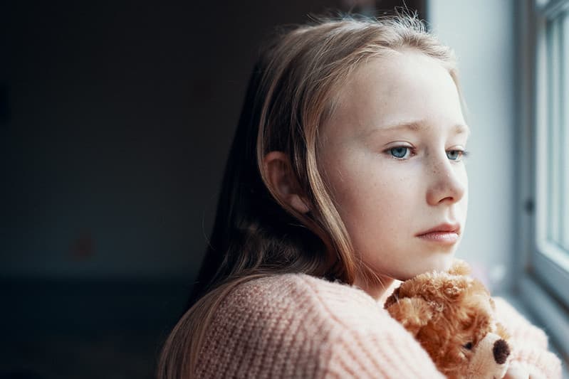 Jente som ser ut av vinduet. Illustrasjonsfoto.