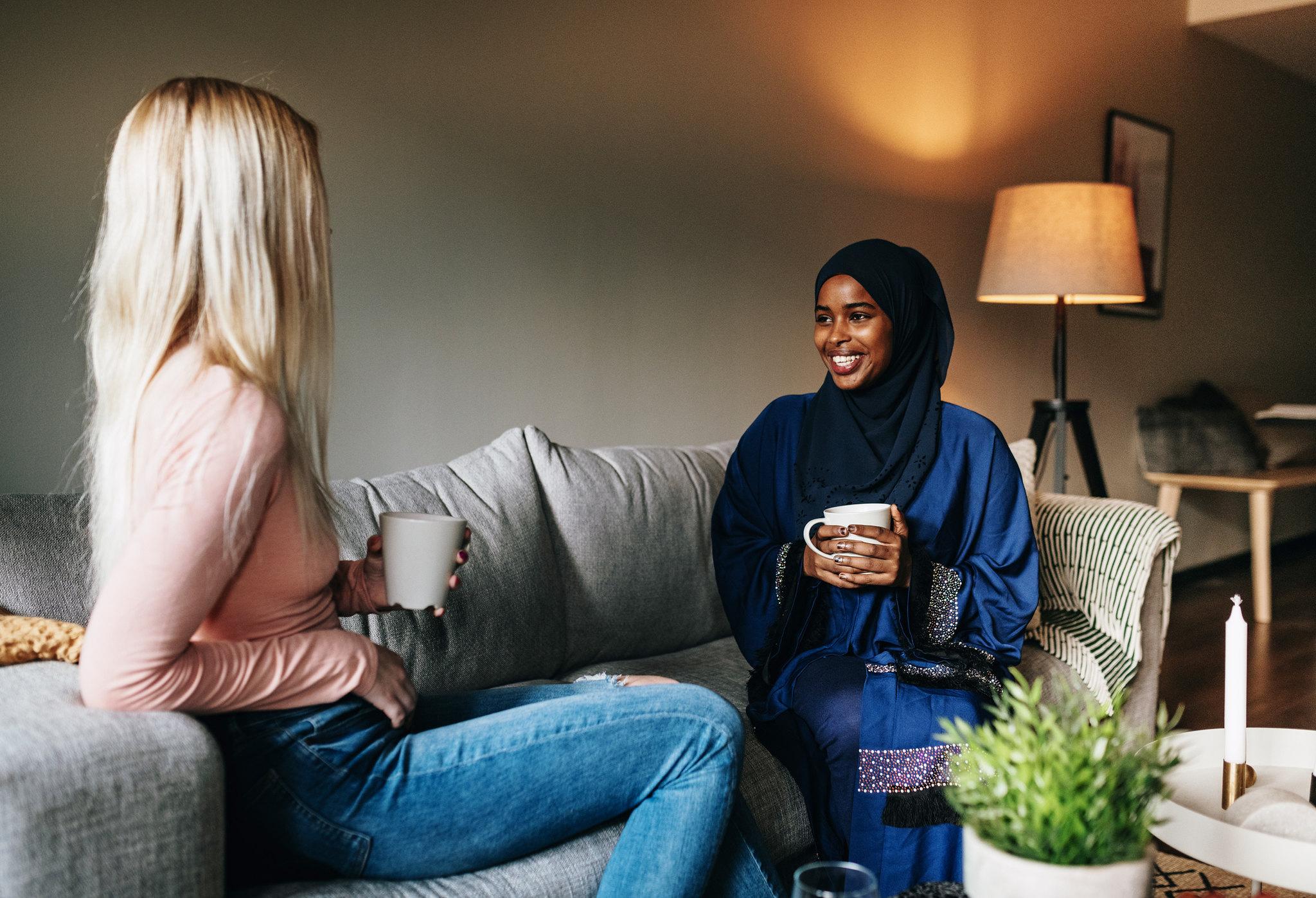 To kvinner sitter i sofa og snakker sammen