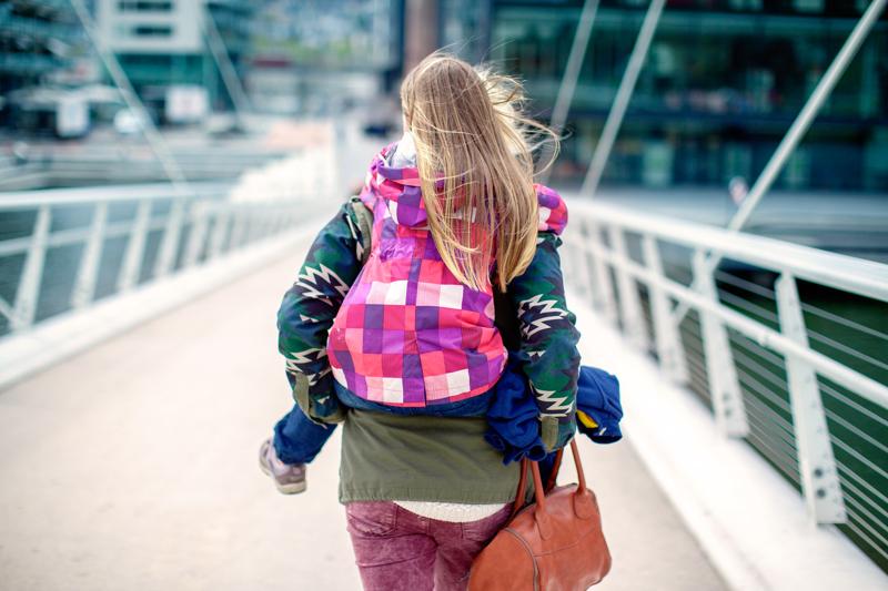 Liten jente som sitter på ryggen til en voksen