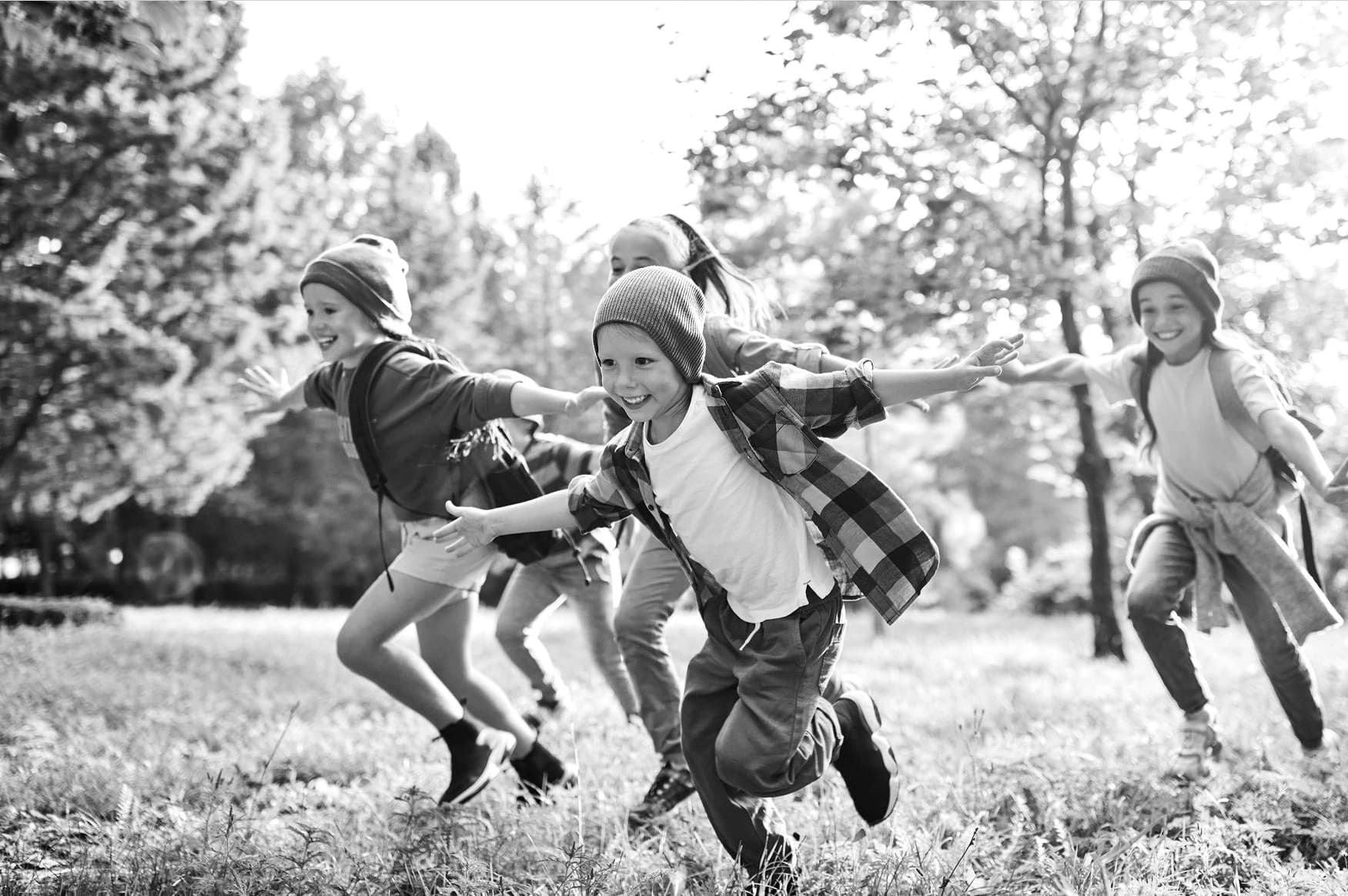 Fire barn som løper på en eng. 