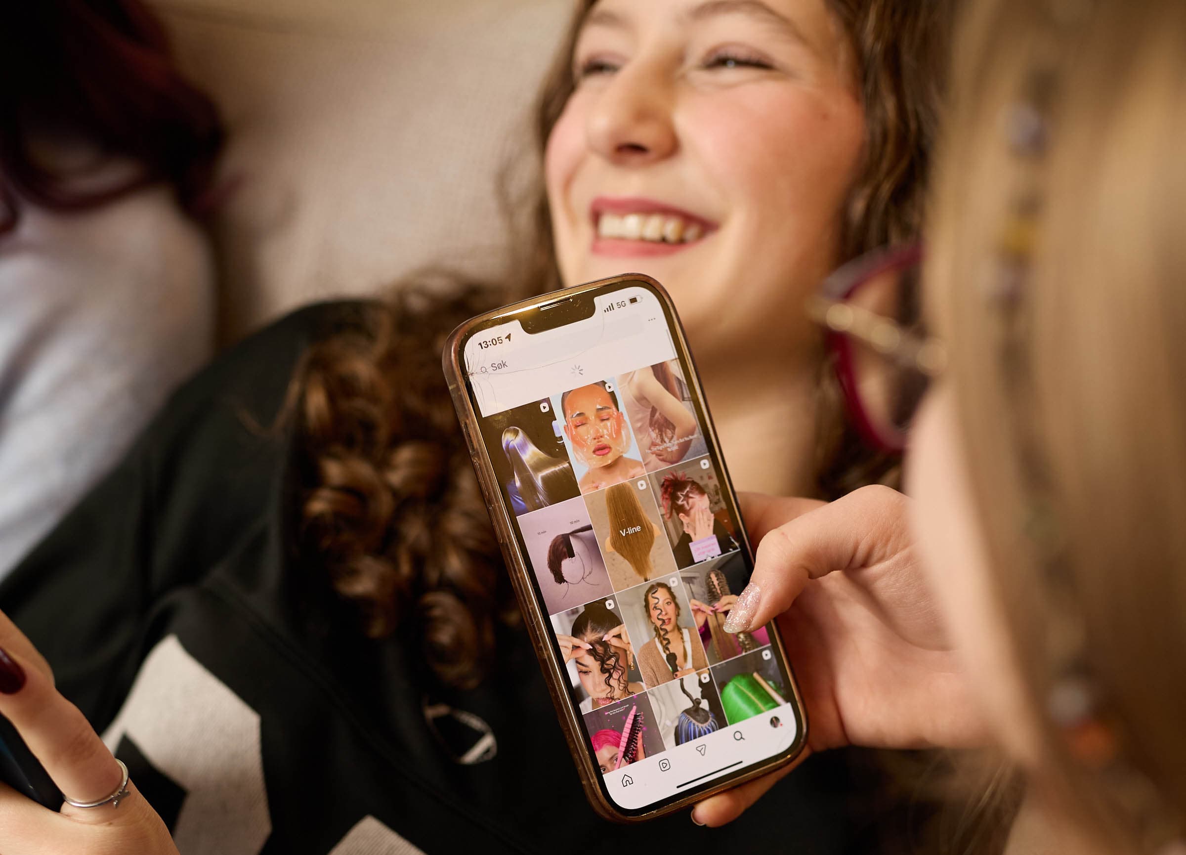 Ung person holder en mobiltelefon som viser en bildestrøm fra et sosialt medium