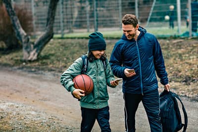 en tenåring og en voksen går med basketball og smiler