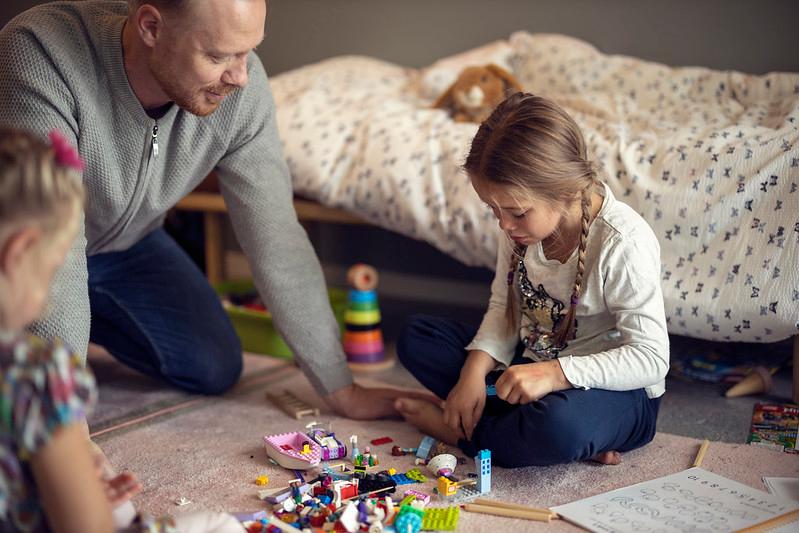far og barn sitter på gulvet og ser på leker