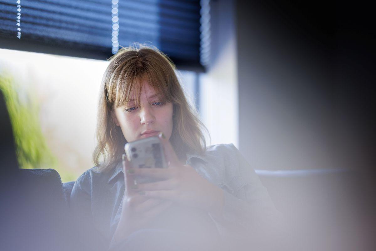 Bildet viser en tenåringsjente som ser på mobilen.