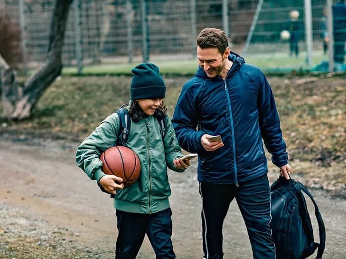 en mann og ungdom med basketball prater og smiler