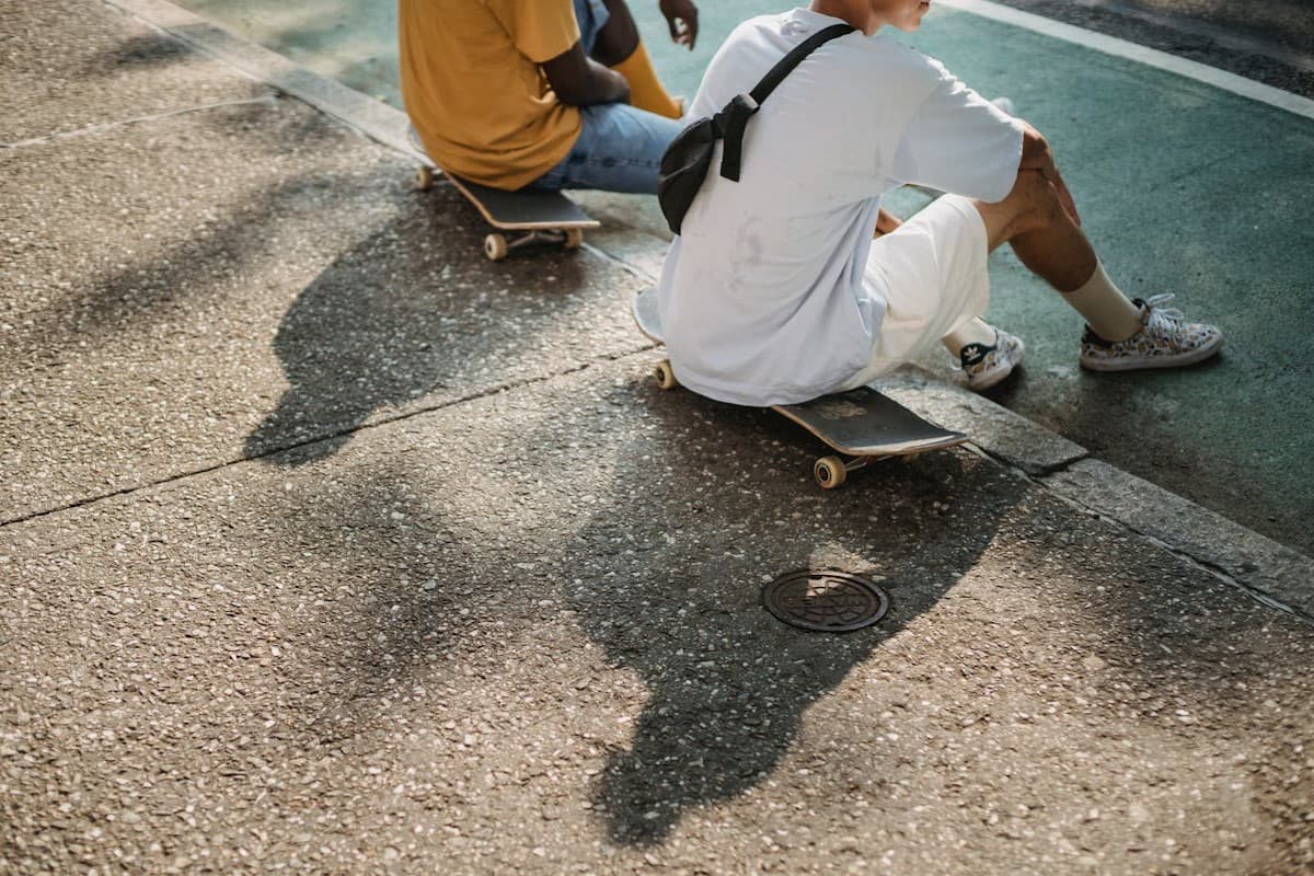 To ungdomsgutter i sommerklær, som sitter på hvert sitt skateboard