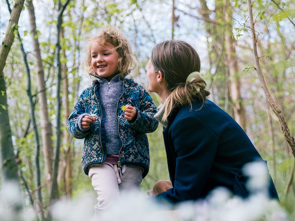 Et barn og en kvinne snakker sammen i en skog