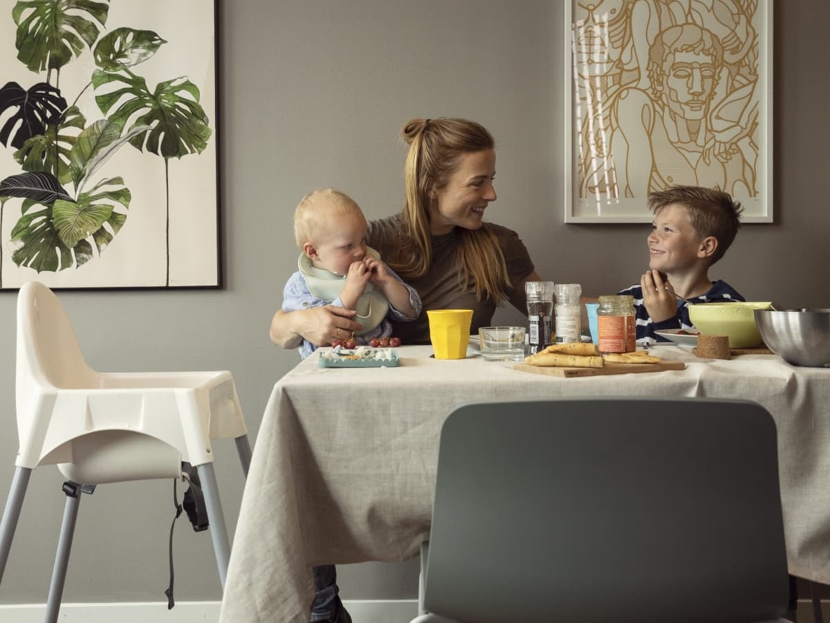 Mor og to barn ved kjøkkenbord.