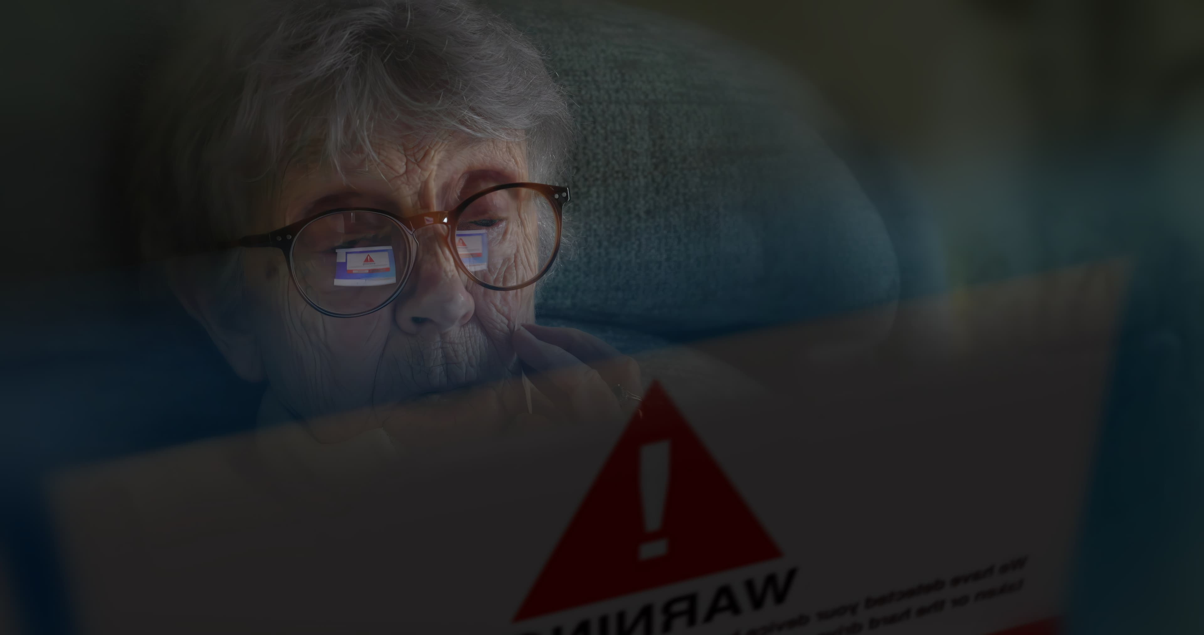 Eldre person som sitter bak skjerm i mørket