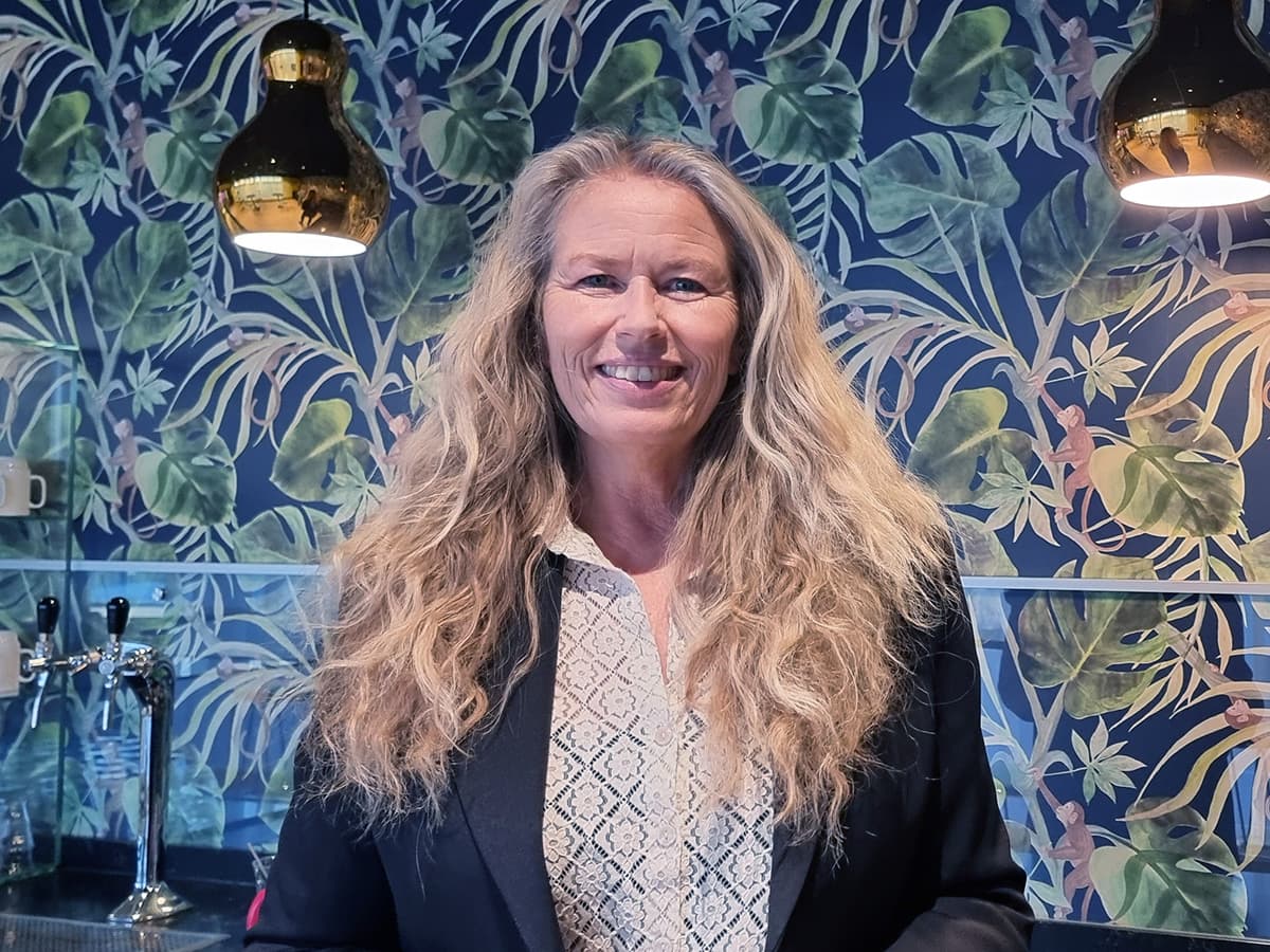 Tone Granaas i sort dressjakke foran fargerikt og møstret tapet