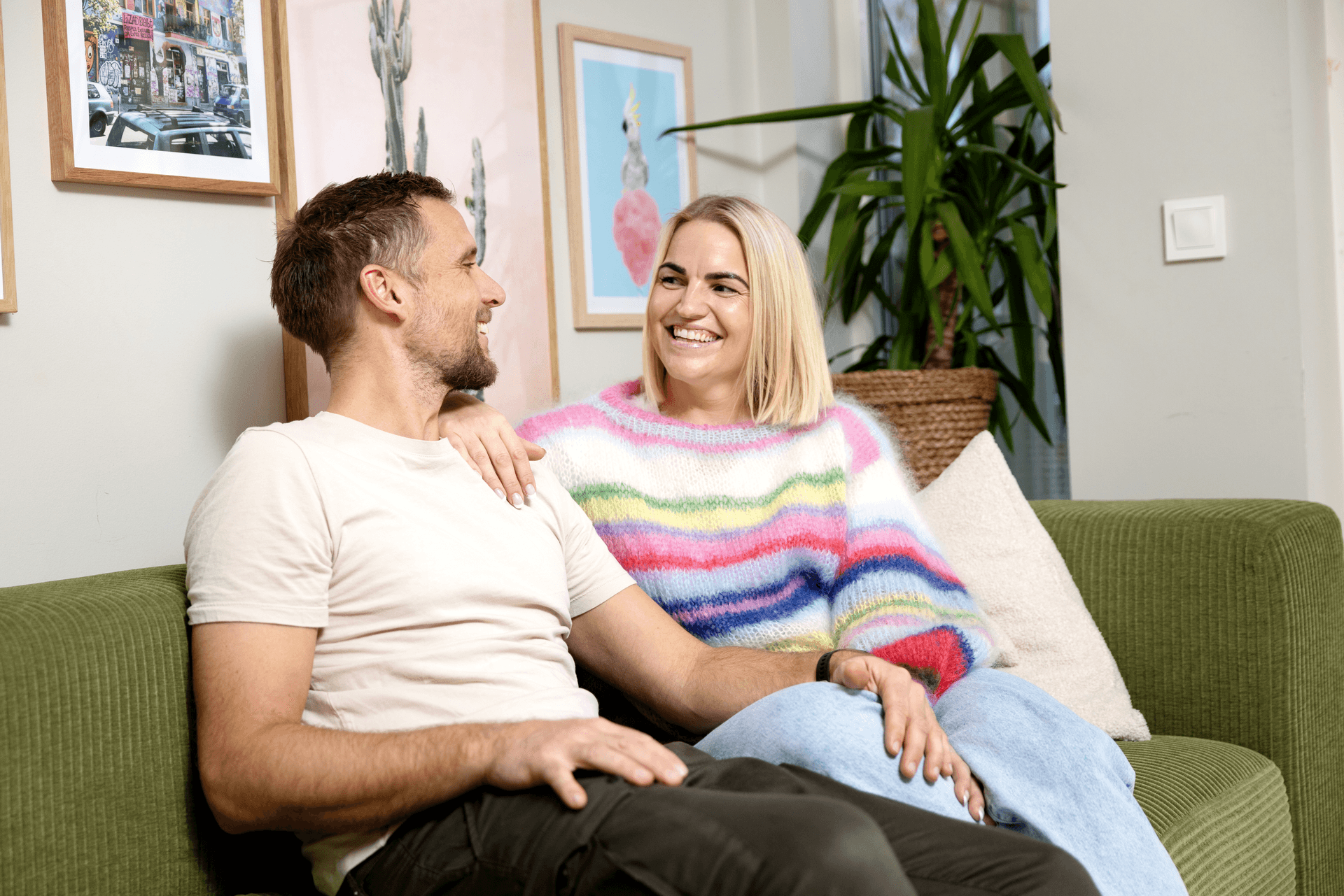 Mann og dame sitter og smiler til hverandre i en sofa