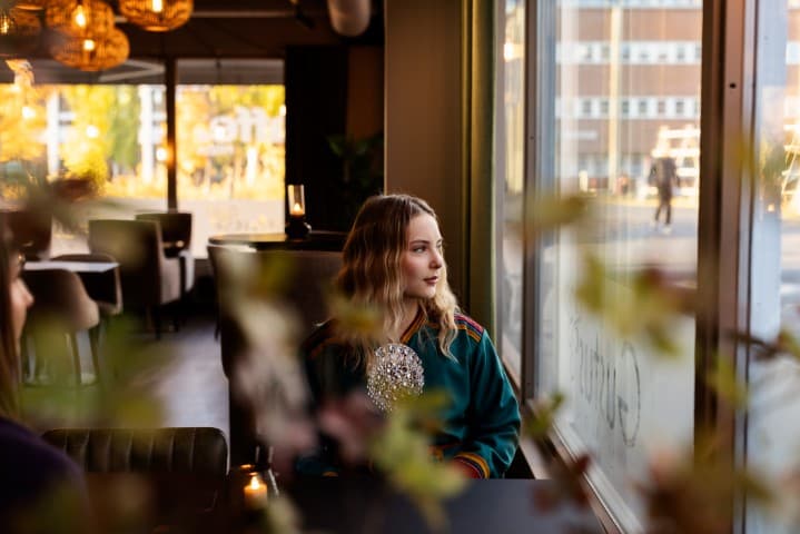 En same i kofte ser ut vinduet