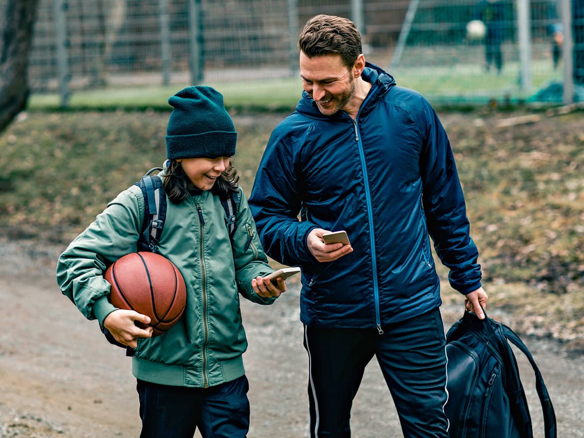 en mann og ungdom med basketball prater og smiler