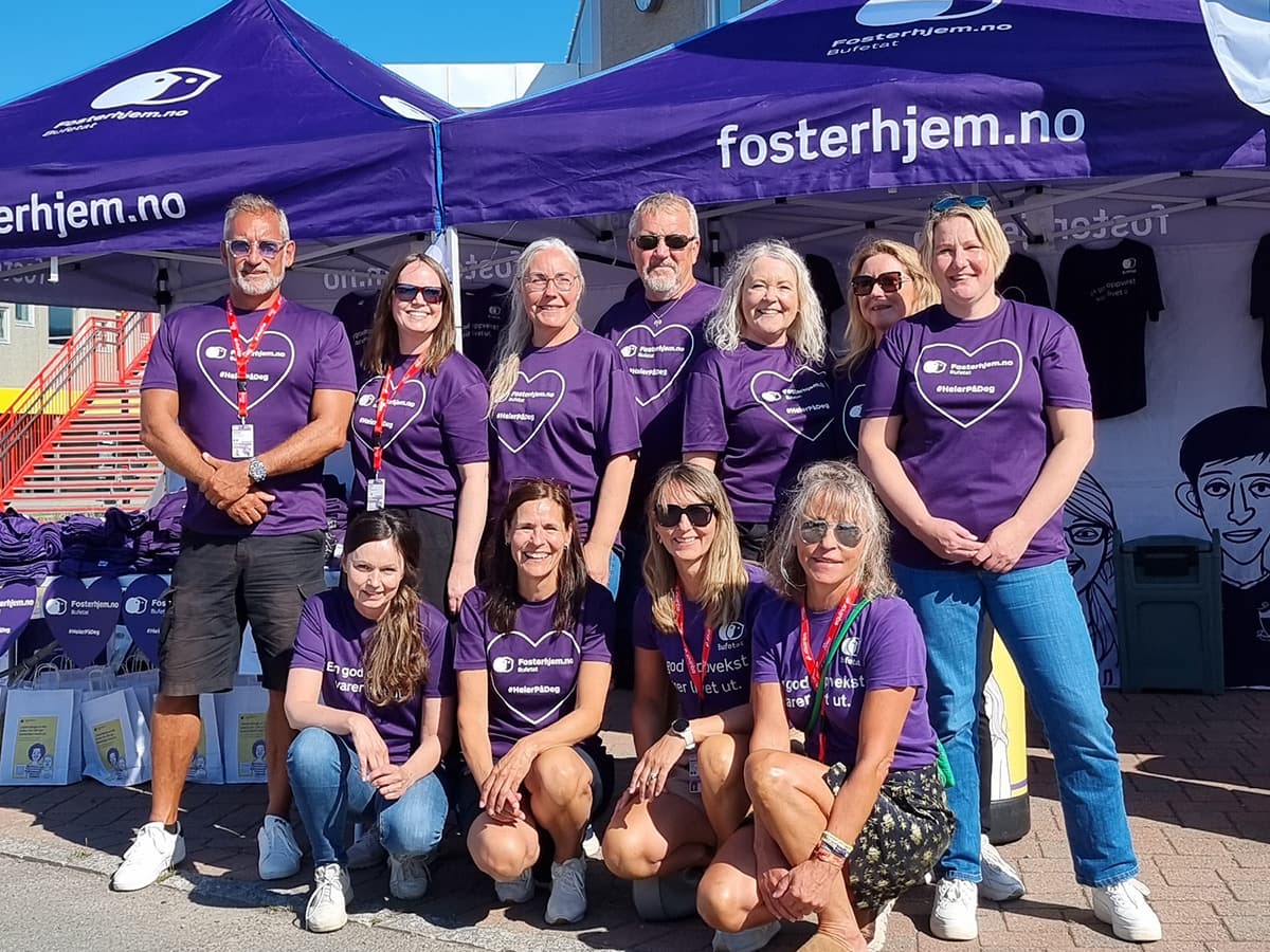 Regiondirektør og ansatte i fosterhjemstjenesten står foran et lilla telt