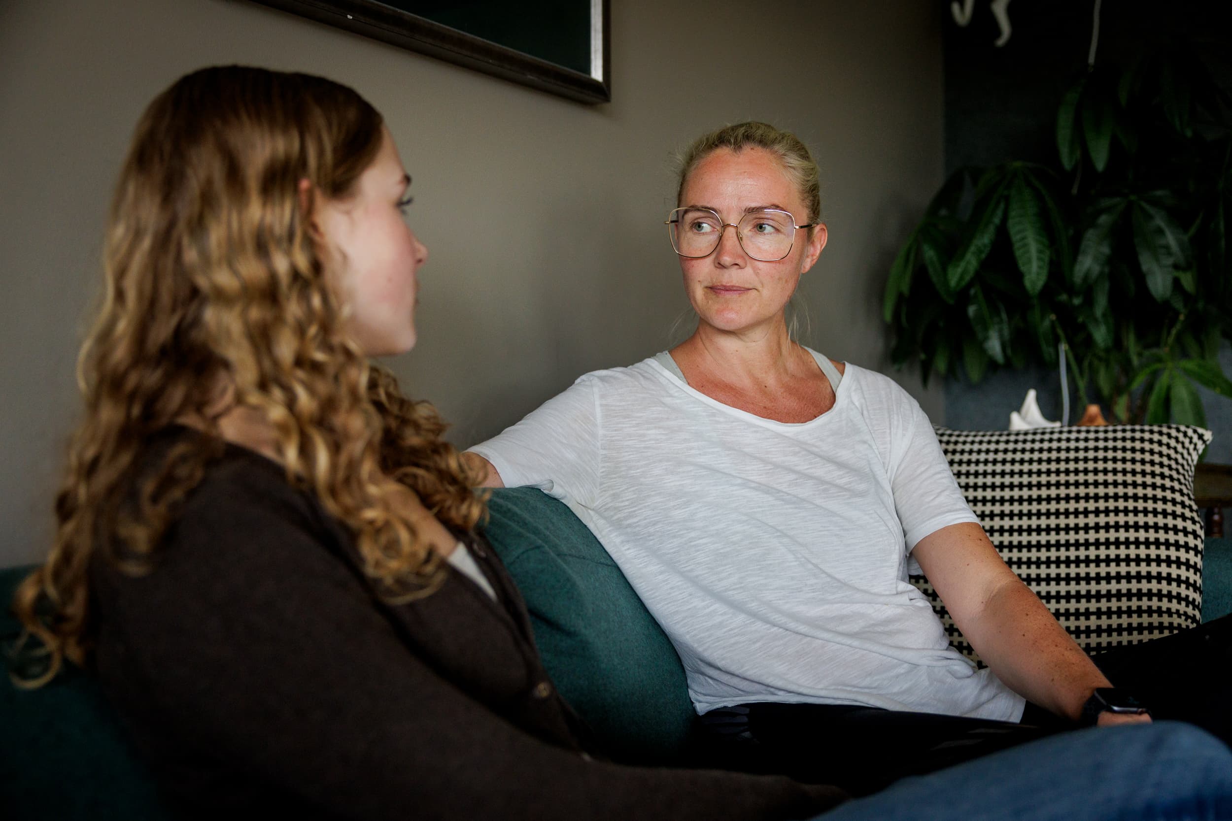 En voksen sitter i sofaen og snakker rolig med en ungdom som sitter ved siden av