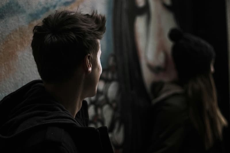 To ungdommer som sitter langs en vegg med grafitti