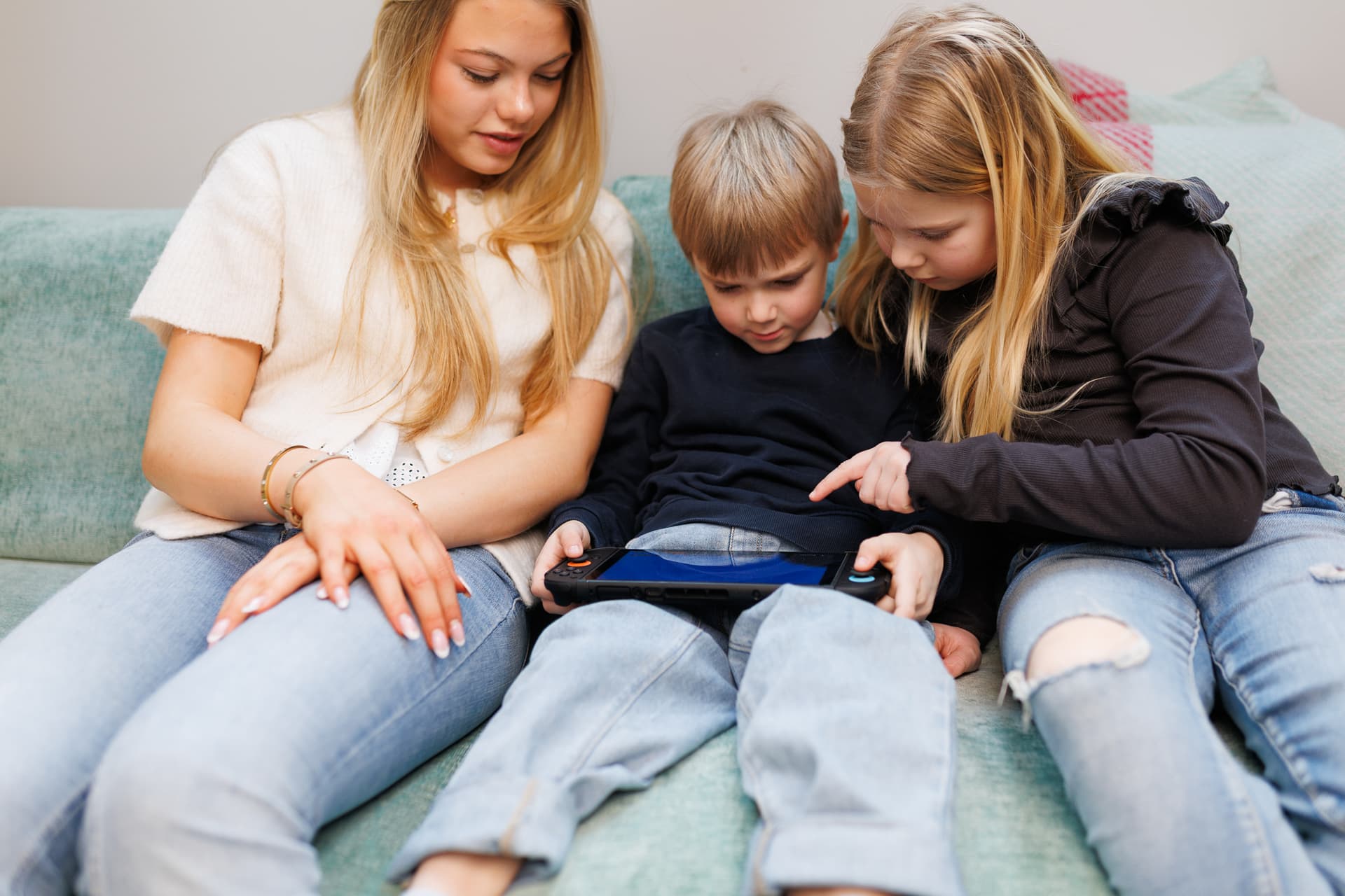 Bildet viser tre barn som ser på en tablet.