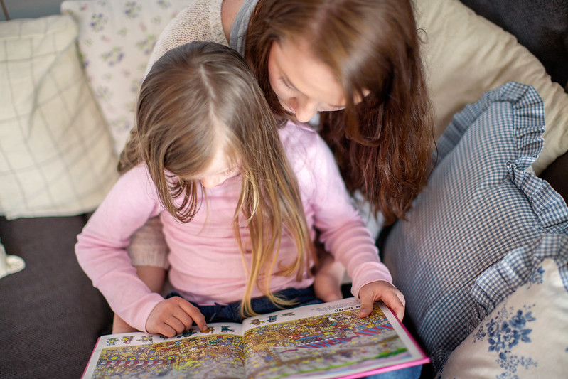 Mor og datter leser tegneserie sammen; ansiktene er ikke synlige
