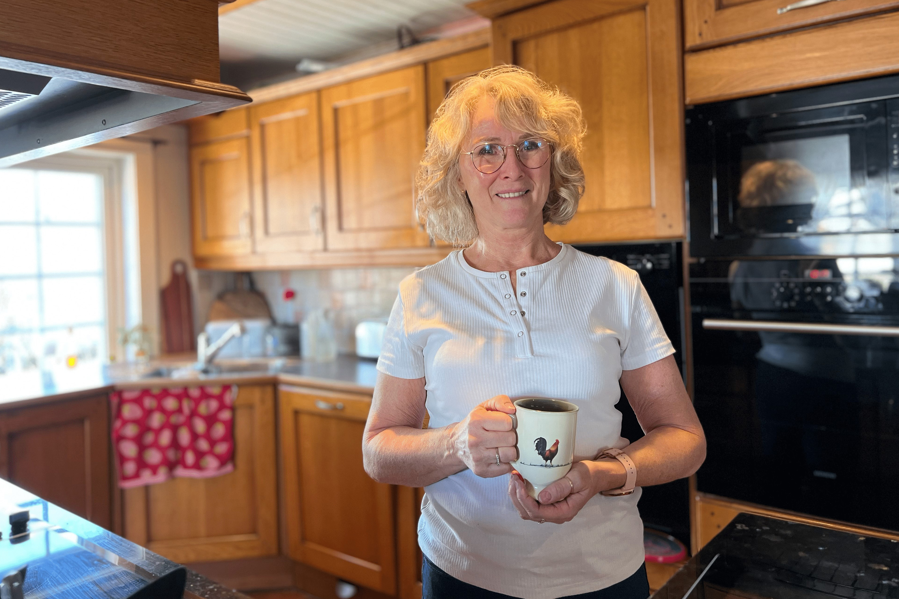 Anne står på kjøkkenet med en kaffekopp i hånden