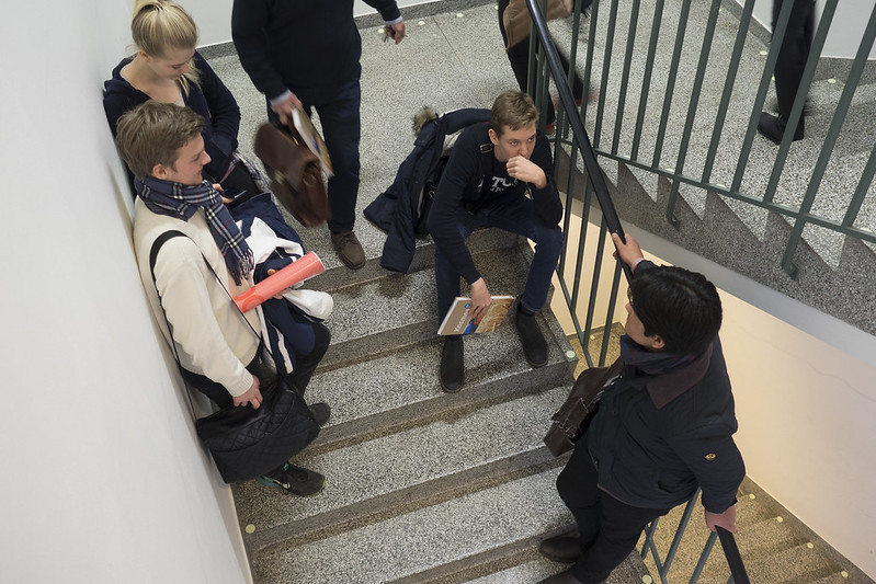 Flere ungdom står i en trappeoppgang av det som virker som en skole 
