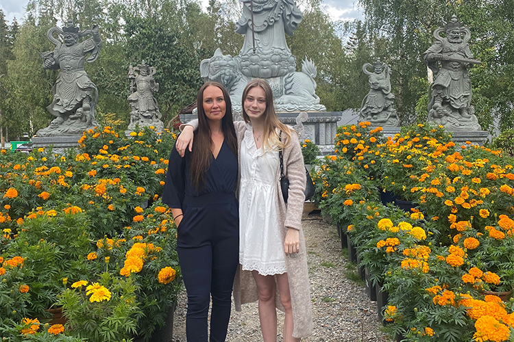 Minna og Lina står i en hage med gule blomster