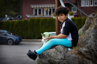 Gutt sitter på en stein ved veien