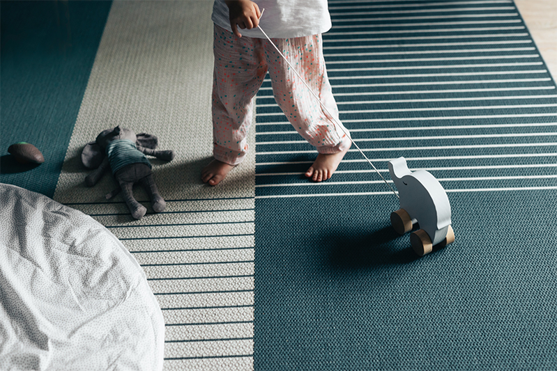 Barn i pysjamas som leker med en treelefant på gulvet
